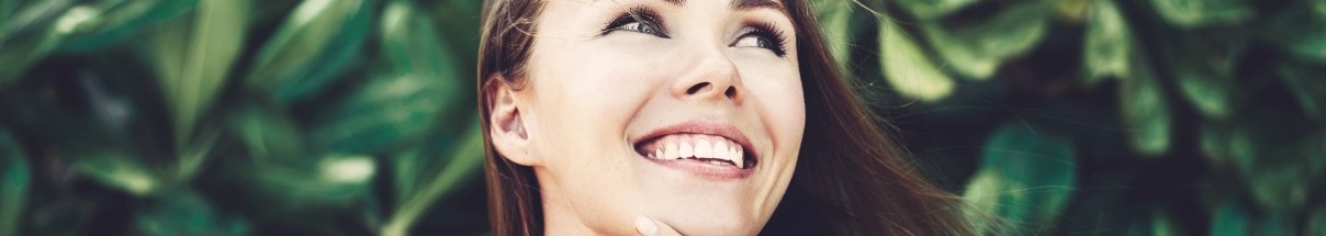 Young woman smiling in front of trees after cosmetic dentistry in Claremore