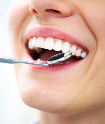 Close up of a mouth with a dental mirror inside of it