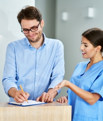 Dental team member showing a patient where to sign on a clipboard