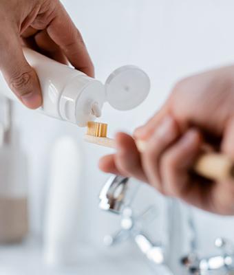Patient putting toothpaste on bristles of toothbrush
