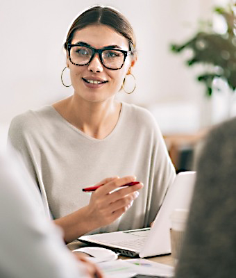 Woman with glasses sitting at desk with laptop