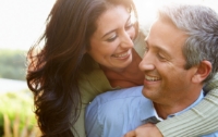 Smiling man and woman holding each other outside at sunset