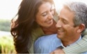 Smiling man and woman holding each other outdoors at sunset