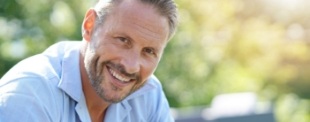 Man in light blue shirt smiling outdoors