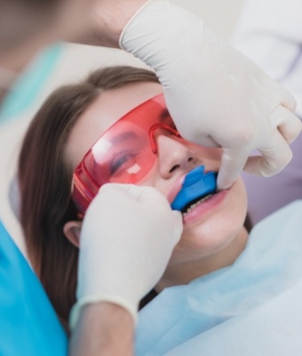 Young woman receiving fluoride treatment in dental office