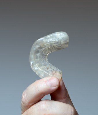 Hand holding a clear nightguard for bruxism