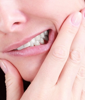 Close up of a person holding their jaw in pain